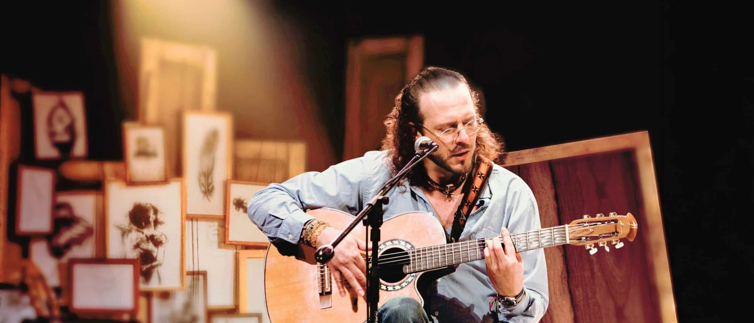 Fernando Delgadillo interpretando una canción en vivo con guitarra acústica durante un concierto íntimo de trova contemporánea